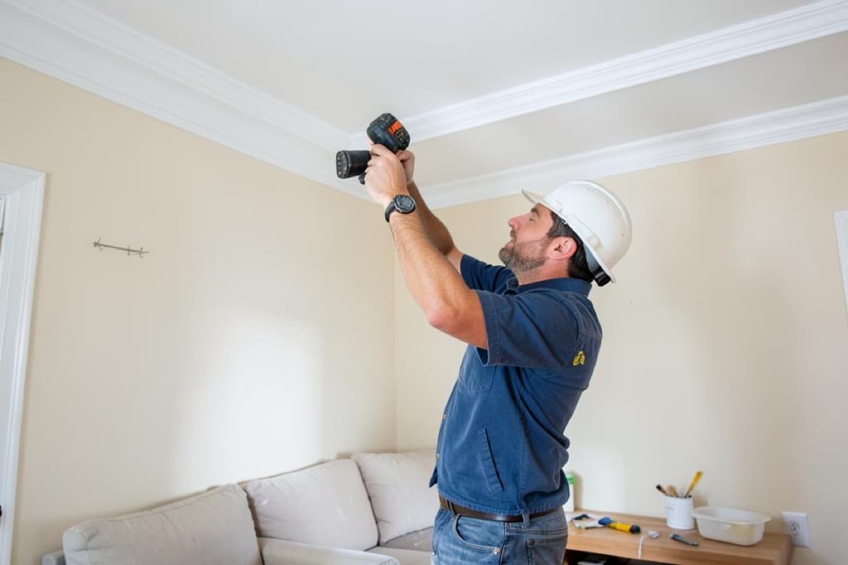 Painter working along crown molding at the ceiling line