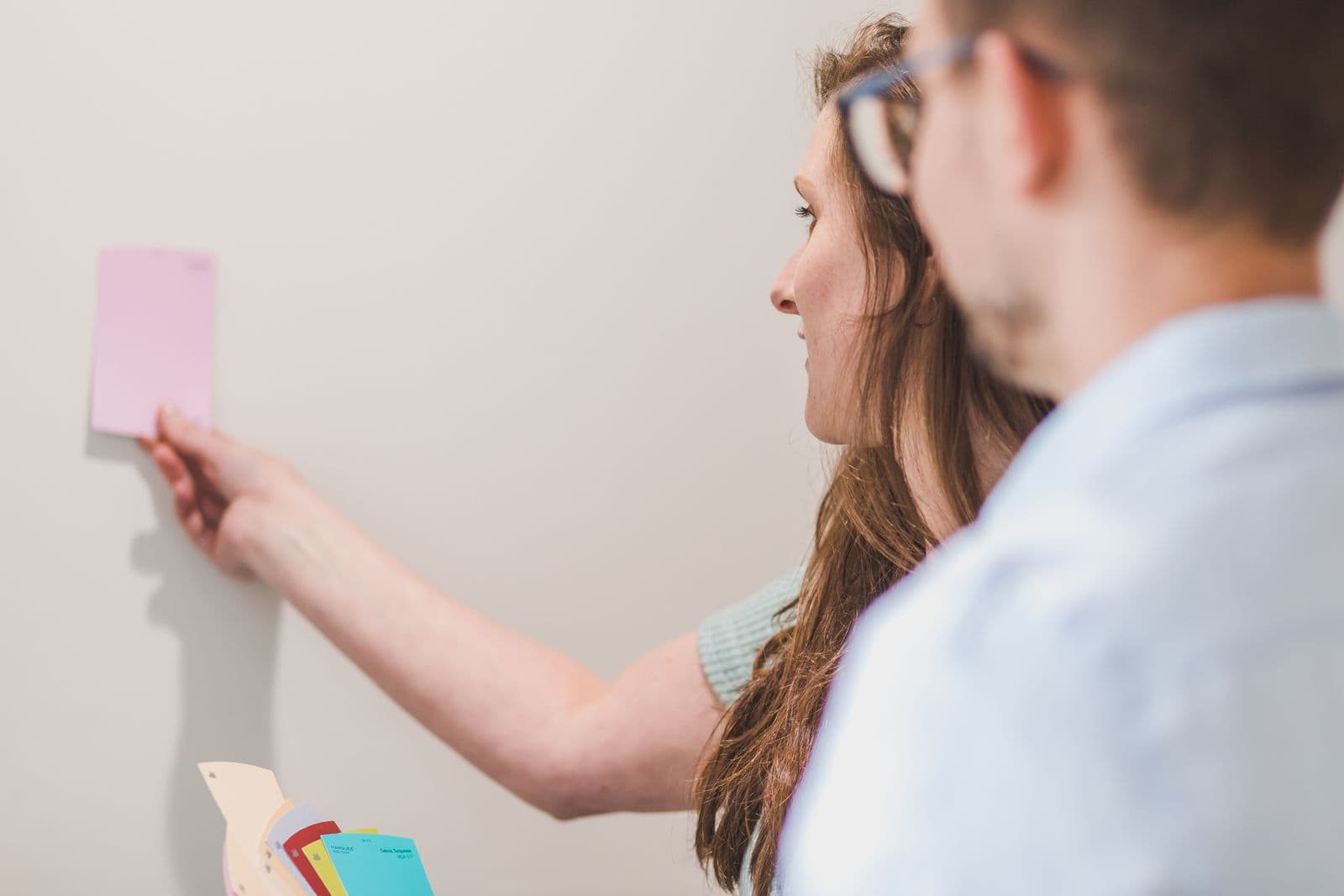 Homeowners holding a paint sample card against the wall