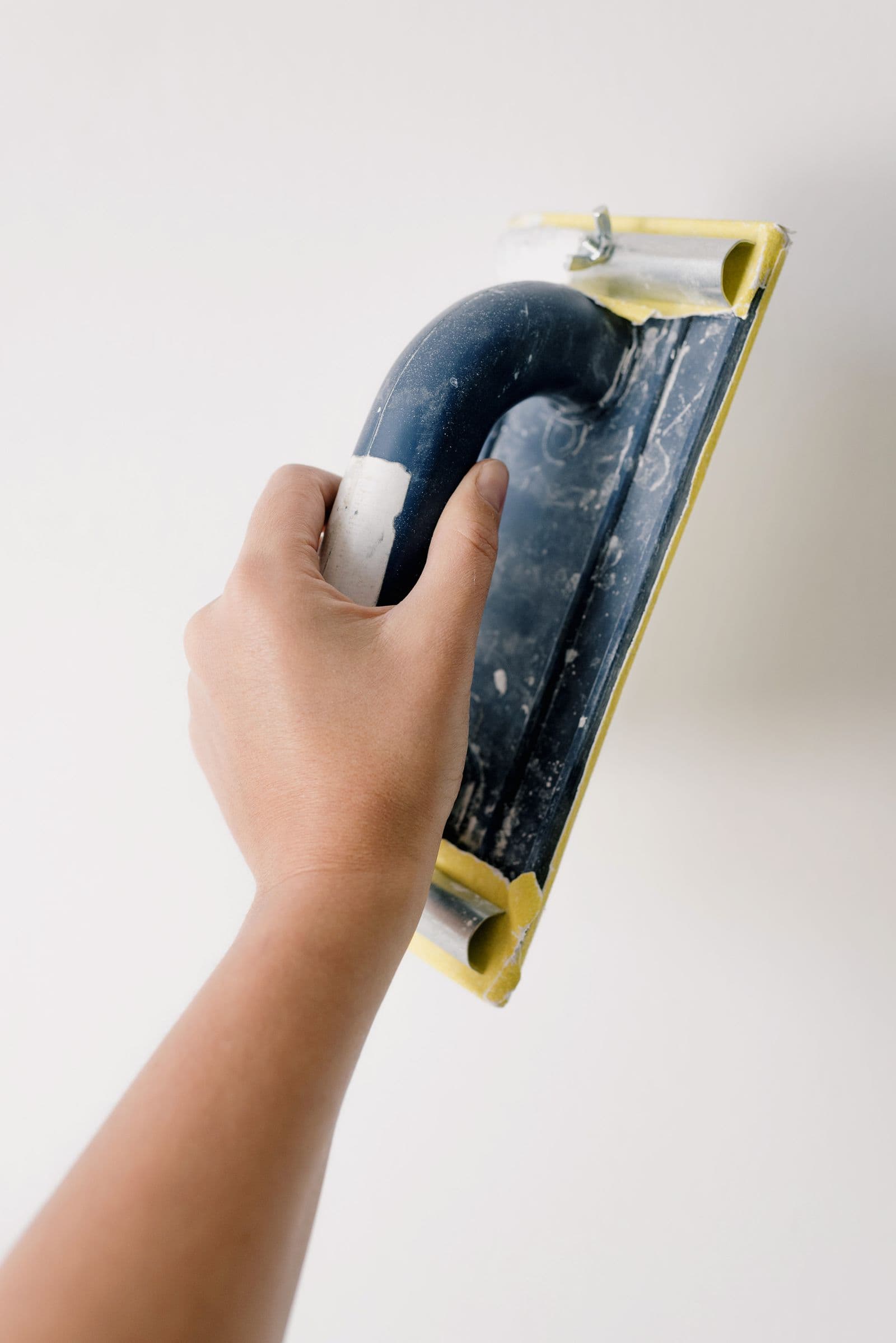 Hand sanding a wall smooth with a sanding block